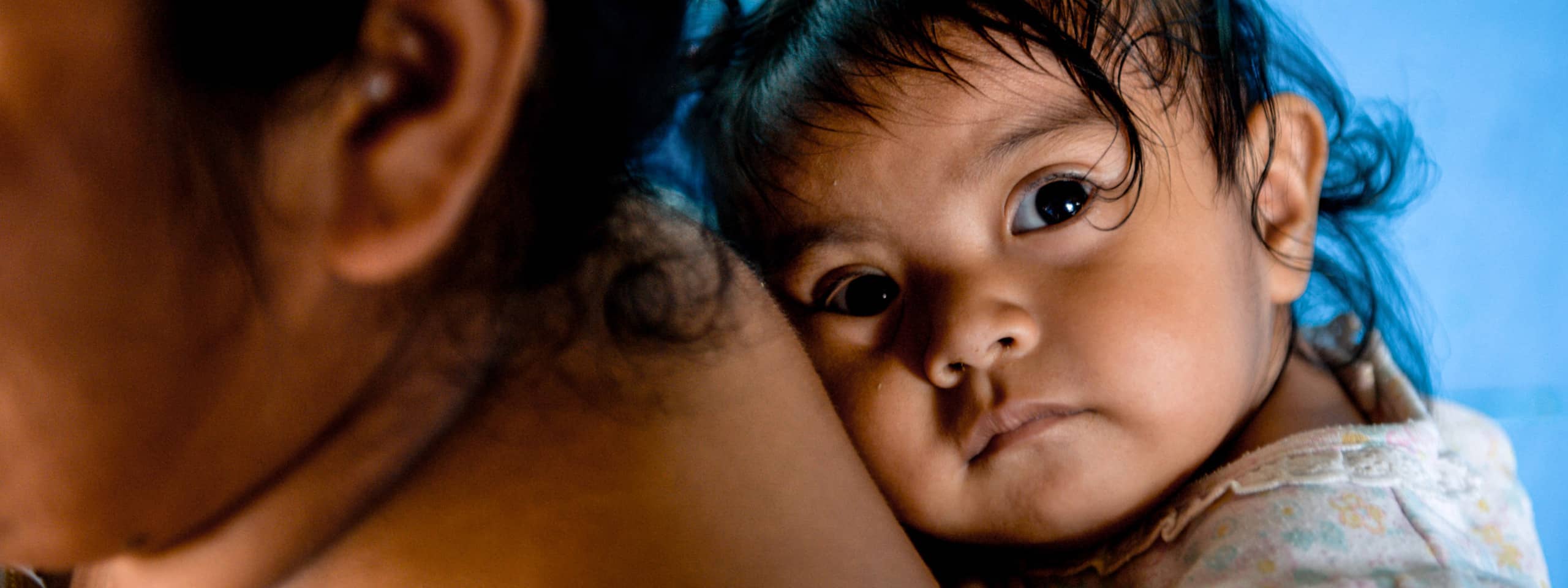 Kleines Mädchen auf Rücken der Mutter, unterstützt durch Spenden für Kinder.
